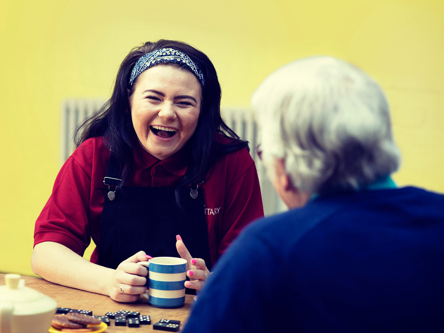A young volunteer enjoying a cup of tea with an older lady 