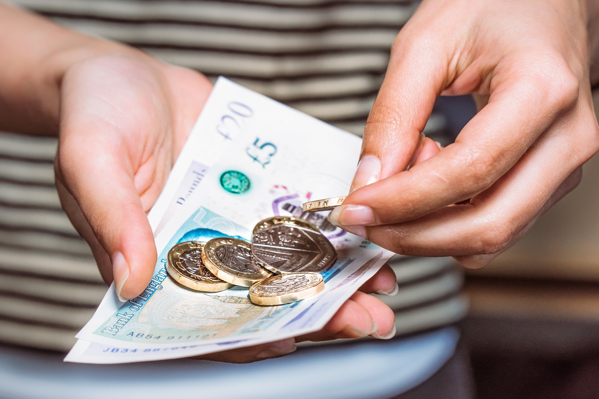 A person holding some cash made up of notes and coins 
