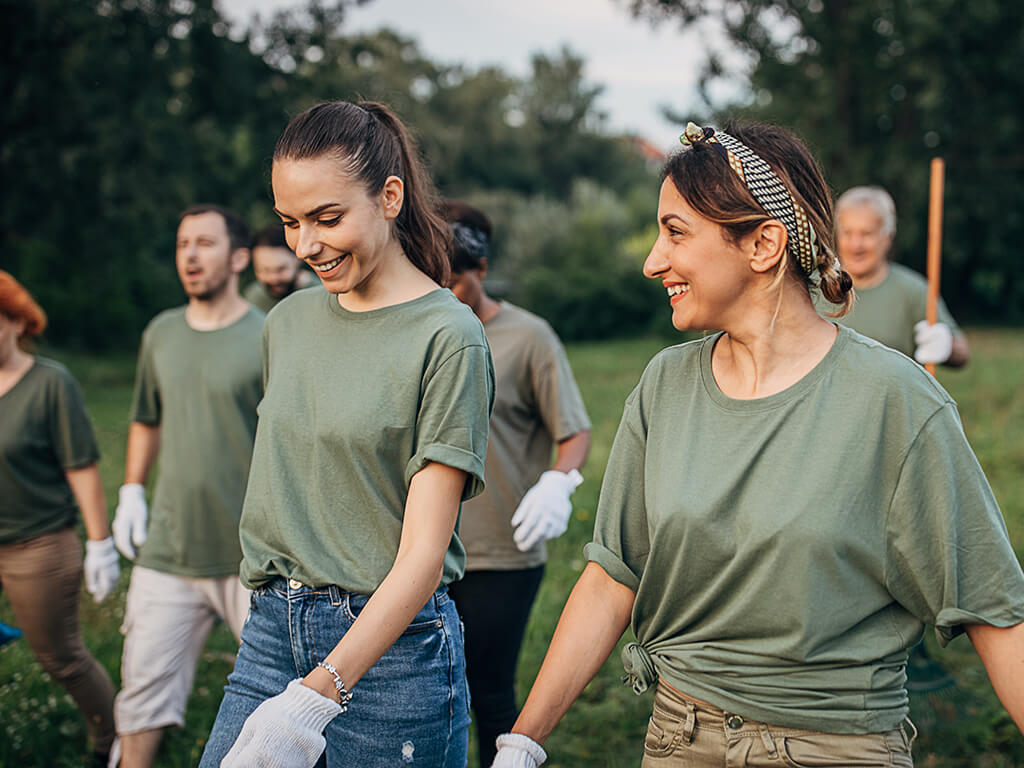 A group of happy volunteers outside doing community volunteering while all wearing similar tshirts 