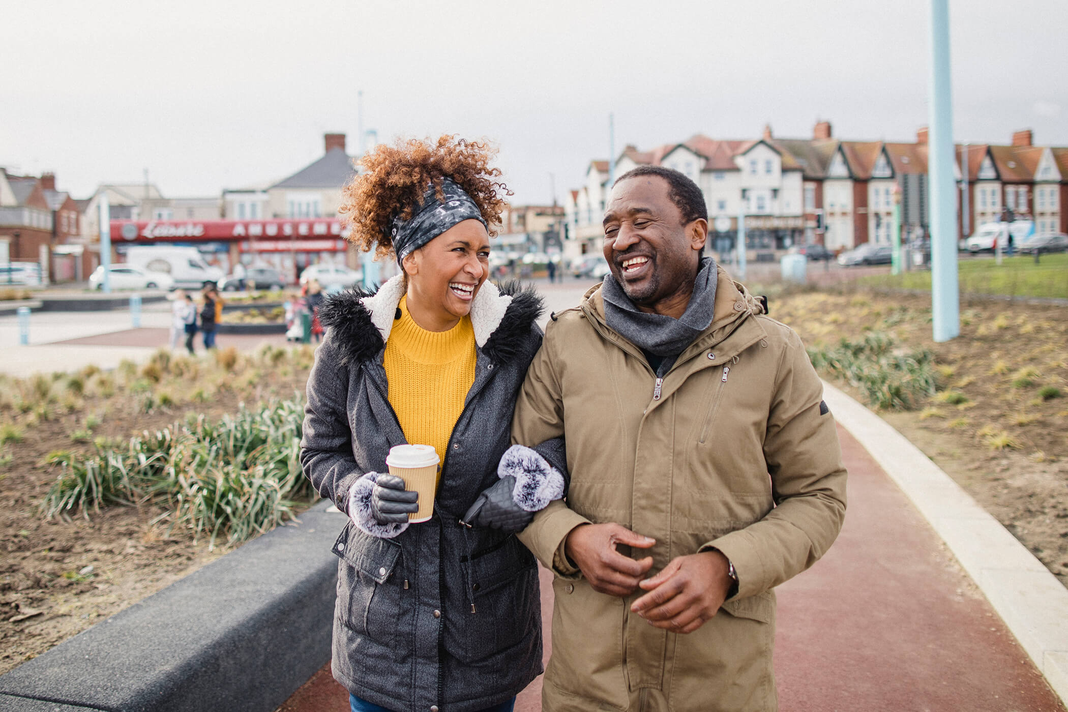 A man and a woman walking arm in arm outside on the street in a city environment