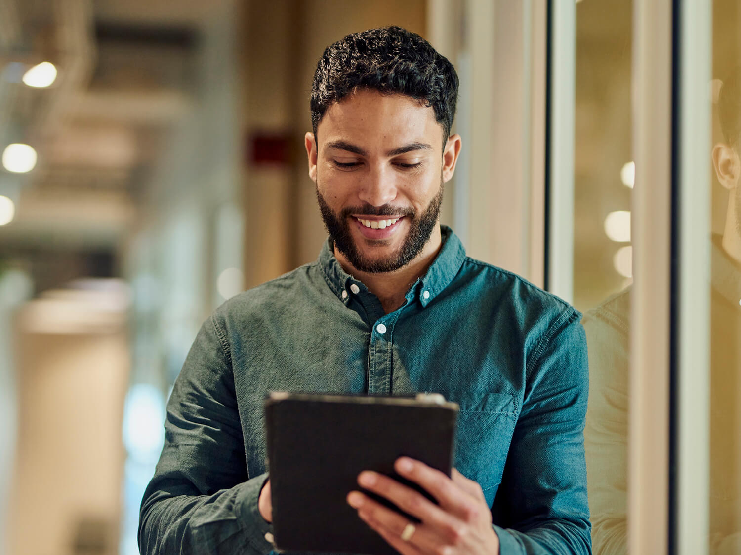 A young man reading a news article on a handheld tablet 